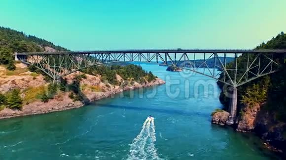 阳光明媚的一天船在海边的桥下航行视频的预览图
