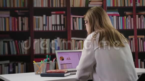 年轻女士在图书馆用笔记本电脑视频的预览图