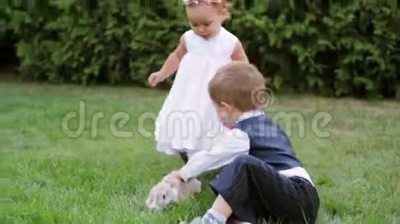 小男孩和小女孩在草地上玩兔子视频的预览图