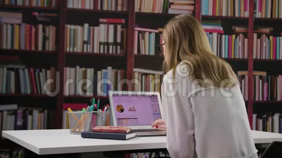 年轻女士在图书馆用笔记本电脑视频的预览图