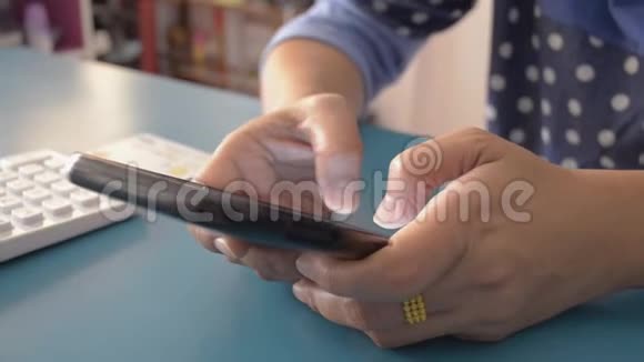 女人在家里的桌子上用智能手机打字短信视频的预览图