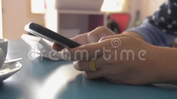女人在家里的桌子上用智能手机打字短信视频的预览图