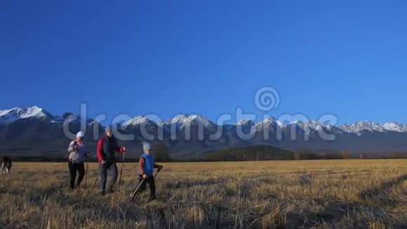 女人在大自然中行走在田野的群山背景下女孩和孩子使用跋涉棒和北欧视频的预览图