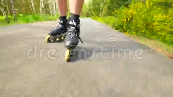在松林的路上滑着滑溜在炎热的夏天曼斯腿在沥青上轮滑近距离观看移动视频的预览图