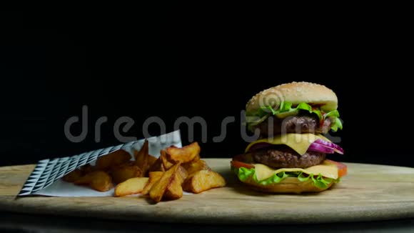 提供美味的汉堡和双奶酪和炸薯条黑色背景视频的预览图