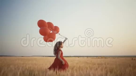 快乐的小女孩在日落时带着气球在麦田里奔跑4k录像视频的预览图