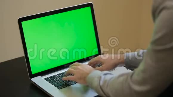 一个男人在笔记本电脑上打字年轻帅哥在绿屏笔记本电脑上的定位及作品视频的预览图