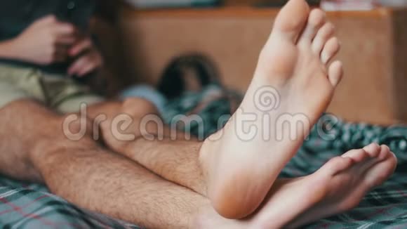 男人的双腿躺在床上消磨空闲时间视频的预览图