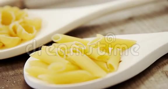 木制背景汤匙里的各种意大利面视频的预览图
