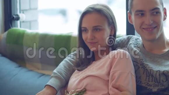 漂亮的年轻夫妇带着愉快的谈话笑坐在窗前视频的预览图