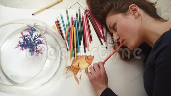 可爱的年轻女艺术家画了一幅小金鱼特写的照片顶部视图视频的预览图