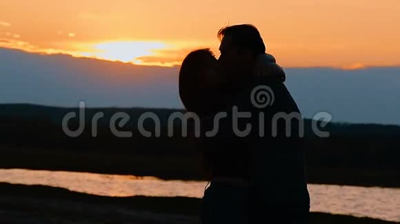 日落时分一个女孩和一个男人接吻的剪影视频的预览图