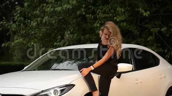美丽的金发年轻女子长发站在白色的汽车附近视频的预览图