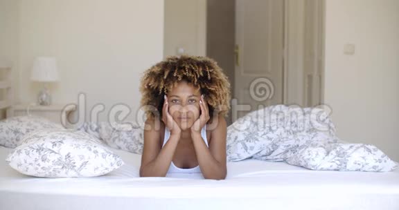 可爱的非洲女人躺在床上看着摄像机视频的预览图