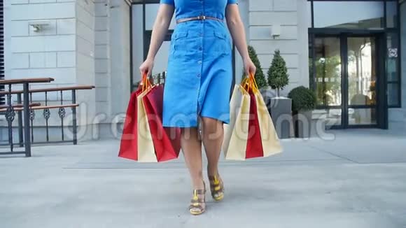 年轻快乐的女人带着购物袋走出商店视频的预览图