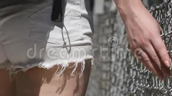 女性手沿网格表面移动年轻女子的手臂接触金属铁丝网女孩在夏天散步视频的预览图