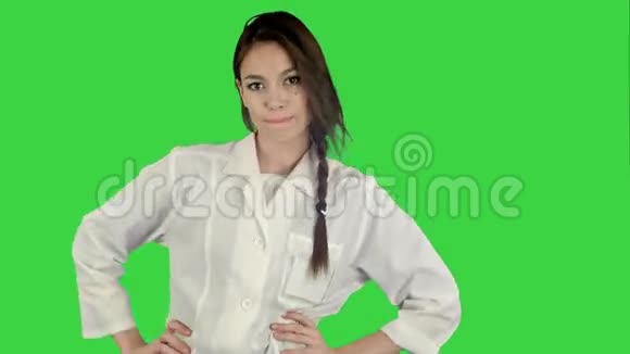 微笑着穿着实验室外套的年轻女子在绿色屏幕上跳着滑稽的舞蹈ChromaKey视频的预览图
