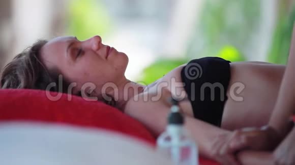 年轻女子躺在热带海滩上放松的水疗沙龙里关闭按摩师做手部按摩视频的预览图