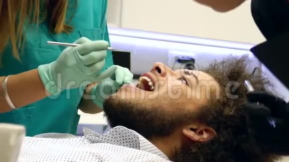 一位女牙医检查一个年轻人的牙齿视频的预览图