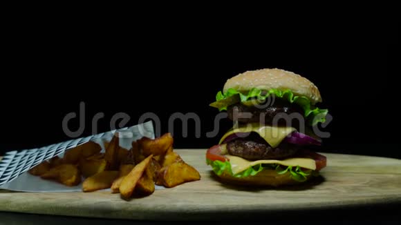 提供美味的汉堡和双奶酪和炸薯条黑色背景视频的预览图