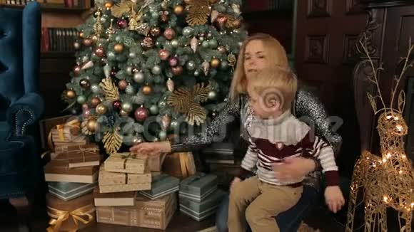 快乐的母亲和她的儿子在圣诞树附近视频的预览图