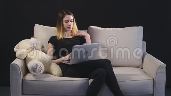 沙发上有笔记本电脑的女孩黑色背景视频的预览图