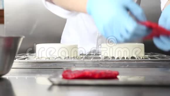 糕点厨师准备蛋糕用糖霜覆盖用草莓装饰在不锈钢工业厨房工作视频的预览图