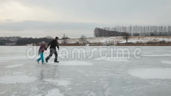 父亲带着女儿在冰冻的湖面上滑冰视频的预览图