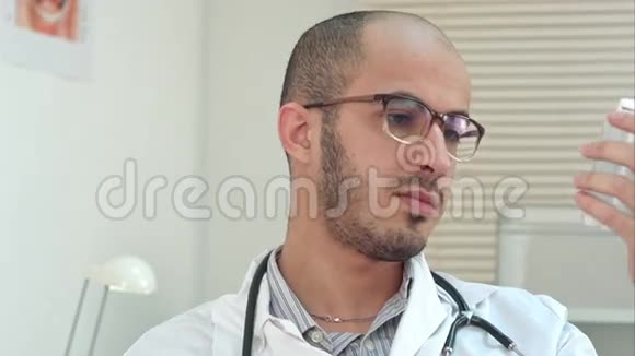 男医生专心阅读一瓶药丸的药标视频的预览图