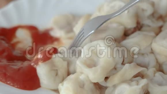 男人用叉子吃饺子把它们放进厨房里的番茄酱视频的预览图