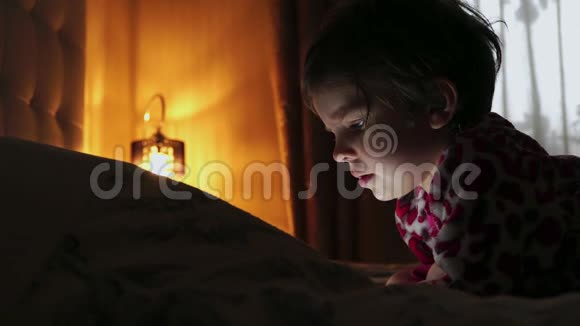 一个在黑暗中看平板电脑的可爱小女孩特写视频的预览图