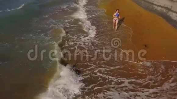 海滩比基尼女郎无忧无虑地沿着海滩上的水奔跑希腊科孚美丽的海岸视频的预览图