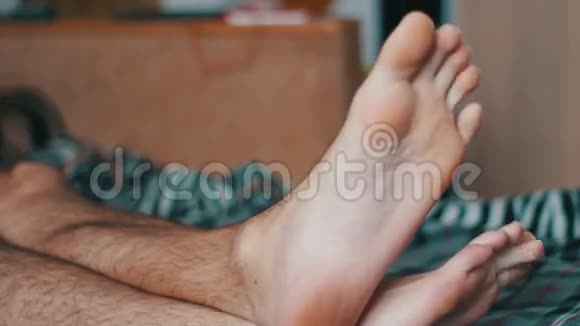 男人的双腿躺在床上消磨空闲时间视频的预览图