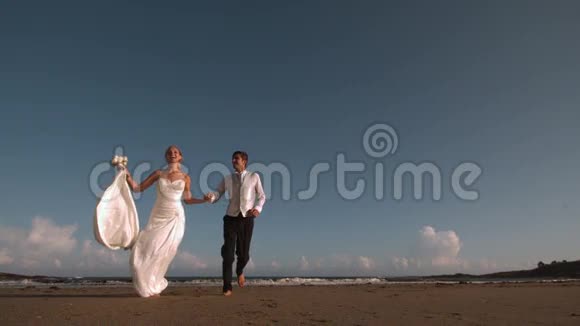 快乐的新婚夫妇在海滩上奔跑视频的预览图