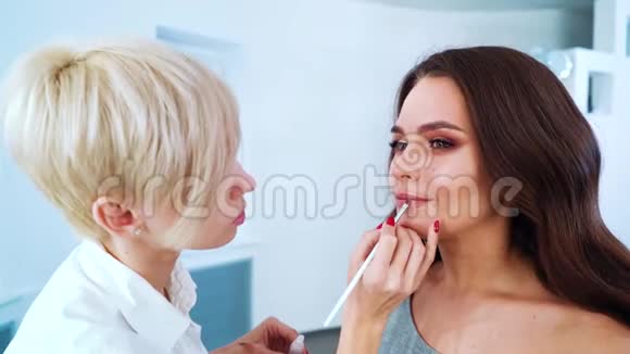 在美容院为年轻美女做专业化妆的女化妆师特写视频的预览图