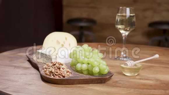 奶酪和葡萄放在木桌上上面有蜂蜜核桃和葡萄酒视频的预览图