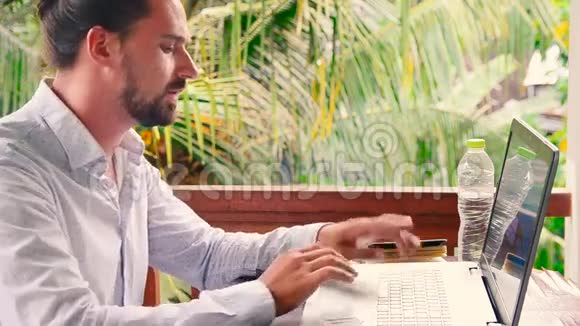 一个商人在读一本计划书和一个思考的想法时用手提电脑工作视频的预览图