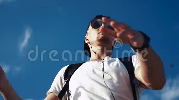 在天空背景上戴着耳机跳舞的年轻人视频的预览图