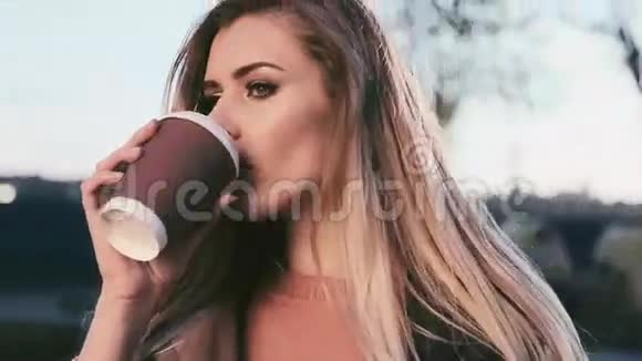 美丽的女人长发在大城市公园散步喝杯咖啡放松和谐穿休闲羊毛西装太阳视频的预览图
