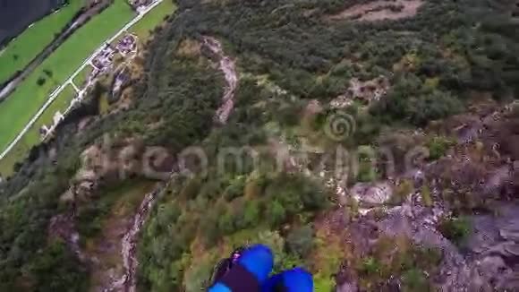 专业跳伞员跳伞在被绿树覆盖的山上体育运动视频的预览图