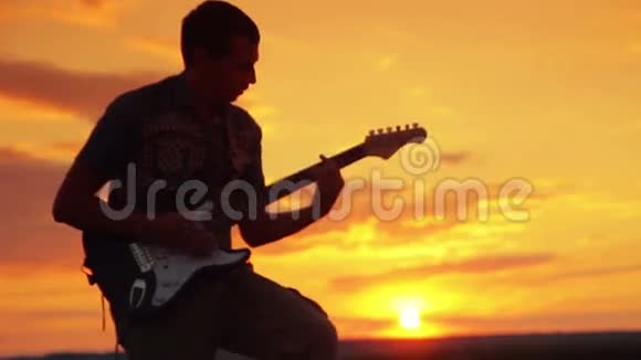 吉他手在日落时在温暖的夏天演奏摇滚视频的预览图