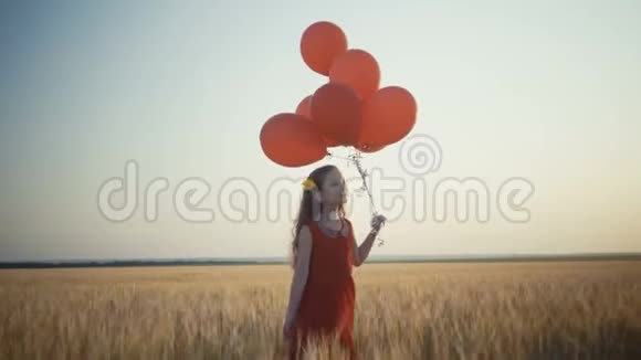 快乐的小女孩在日落时带着气球在麦田里奔跑4k录像视频的预览图