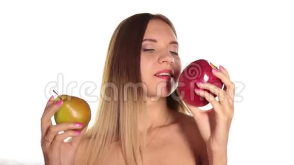 赤裸的年轻女人涂着红色的口红把头发放下来刷了一下吃了一个又大又黑的红苹果和多汁的梨视频的预览图