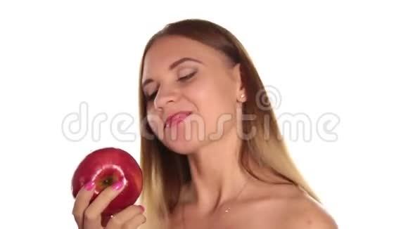 赤裸的年轻女人涂着红色的口红把头发放下来刷了一下吃了一个又大又黑的红苹果健康食品视频的预览图