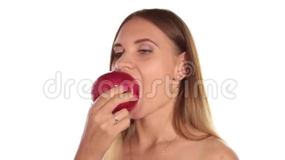 赤裸的年轻女人涂着红色的口红把头发放下来刷了一下吃了一个又大又黑的红苹果健康食品视频的预览图