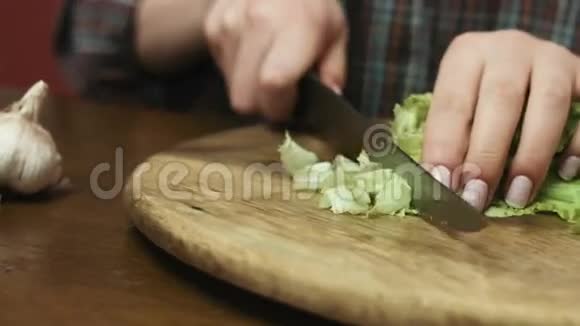 女人在厨房的切割板上用大刀切碎新鲜的绿色卷心菜视频的预览图