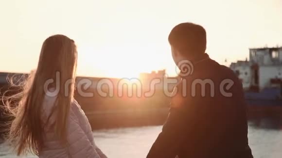 迷人的浪漫情侣看着港口里的船在海港散步享受美丽的日落视频的预览图