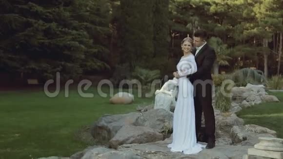 一对新婚夫妇站在绿色公园里视频的预览图