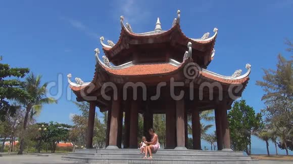 母亲和女儿坐在有柱子的美丽佛教建筑的台阶上视频的预览图