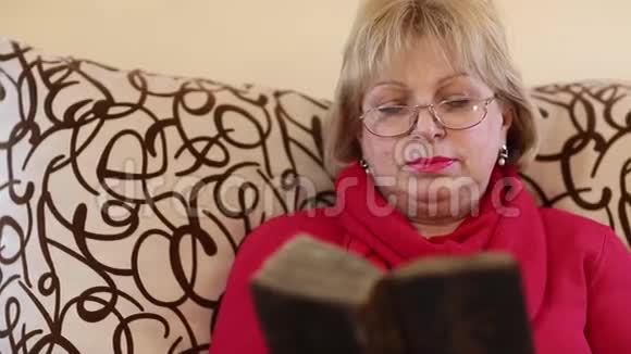 一位年长的妇女坐在一位女牧师的椅子上读一本旧书视频的预览图